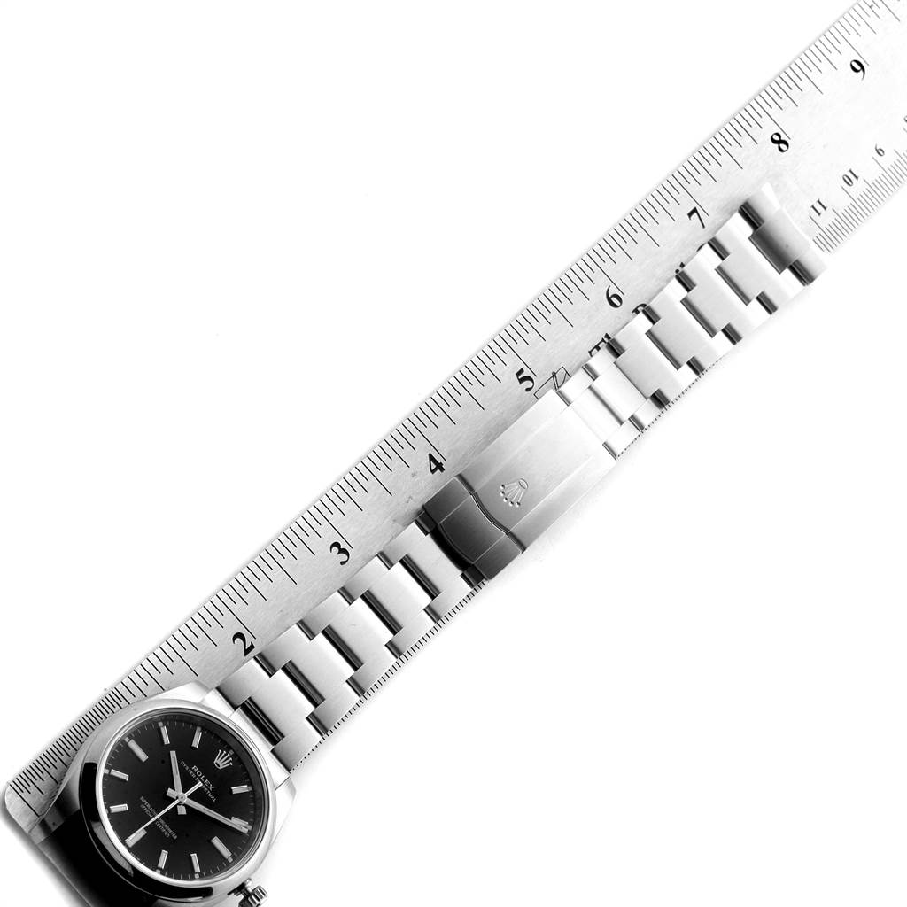The image shows a Rolex Oyster Perpetual 114200 Men
s Stainless Steel Black Dial 114200 Men
s Stainless Steel Black Dial watch laid flat with a ruler measuring its bracelet length.