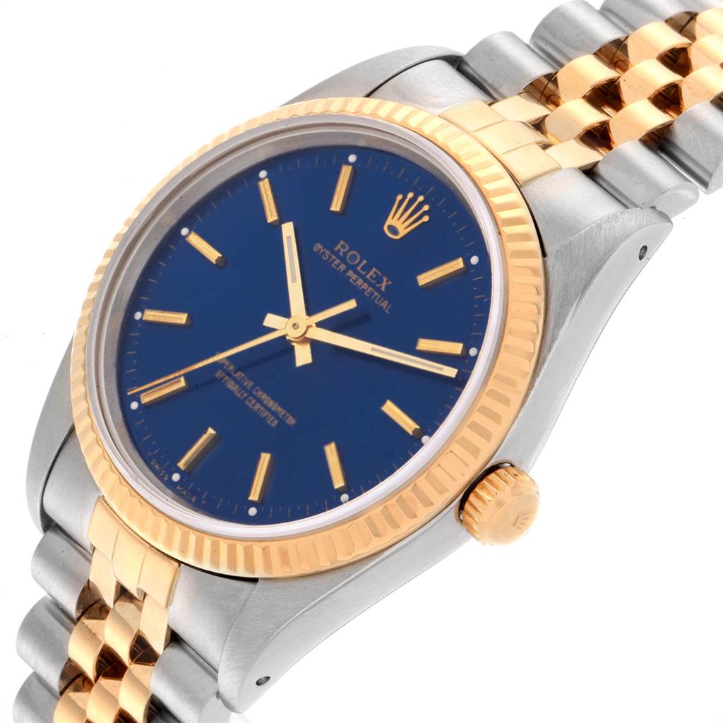 The image shows a close-up angle of a Rolex Oyster Perpetual 14233 Men's Steel and Gold (two tone) Blue Dial 14233 Men's Steel and Gold (two tone) Blue Dial watch, highlighting its blue dial, gold bezel, and two-tone bracelet.