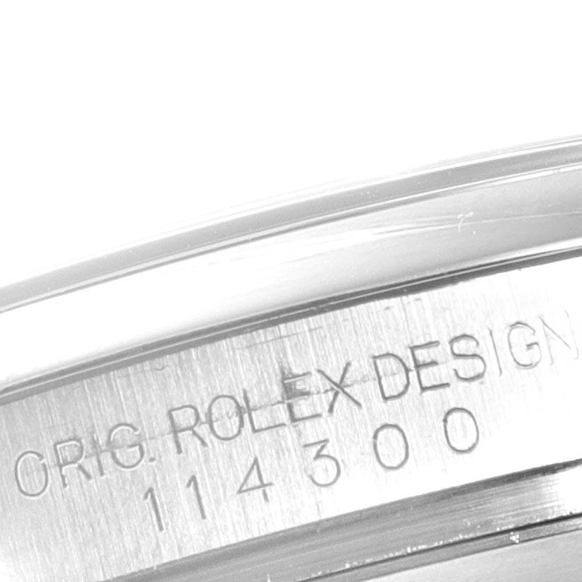 The image shows a close-up of the engraving on the side of the case of a Rolex Oyster Perpetual 114300 Men's Stainless Steel Blue Dial 114300 Men's Stainless Steel Blue Dial watch.