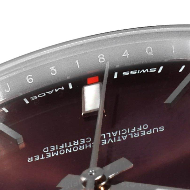 This close-up angle shows the dial and hands of the Rolex Oyster Perpetual 114300 Men's Stainless Steel Burgundy Dial 114300 Men's Stainless Steel Burgundy Dial watch, highlighting the text and part of the bezel.