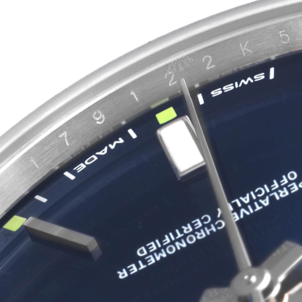 The image shows a close-up view of the dial and the edge of the bezel of a Rolex Oyster Perpetual 114300 Men
s Stainless Steel Blue Dial 114300 Men
s Stainless Steel Blue Dial watch.