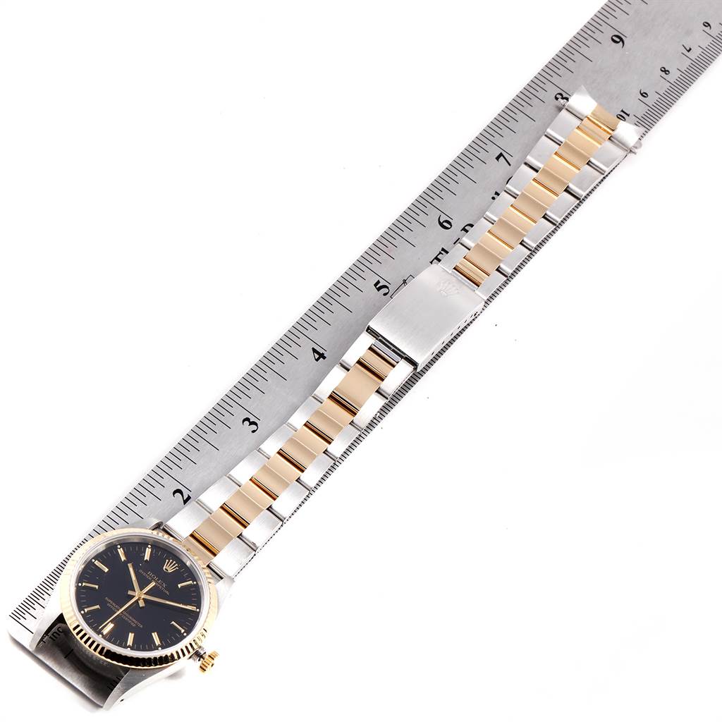 The image shows a side view of a Rolex Oyster Perpetual 14233 Men's Steel and Gold (two tone) Black Dial 14233 Men's Steel and Gold (two tone) Black Dial watch highlighting the face, bezel, and bracelet with a ruler.