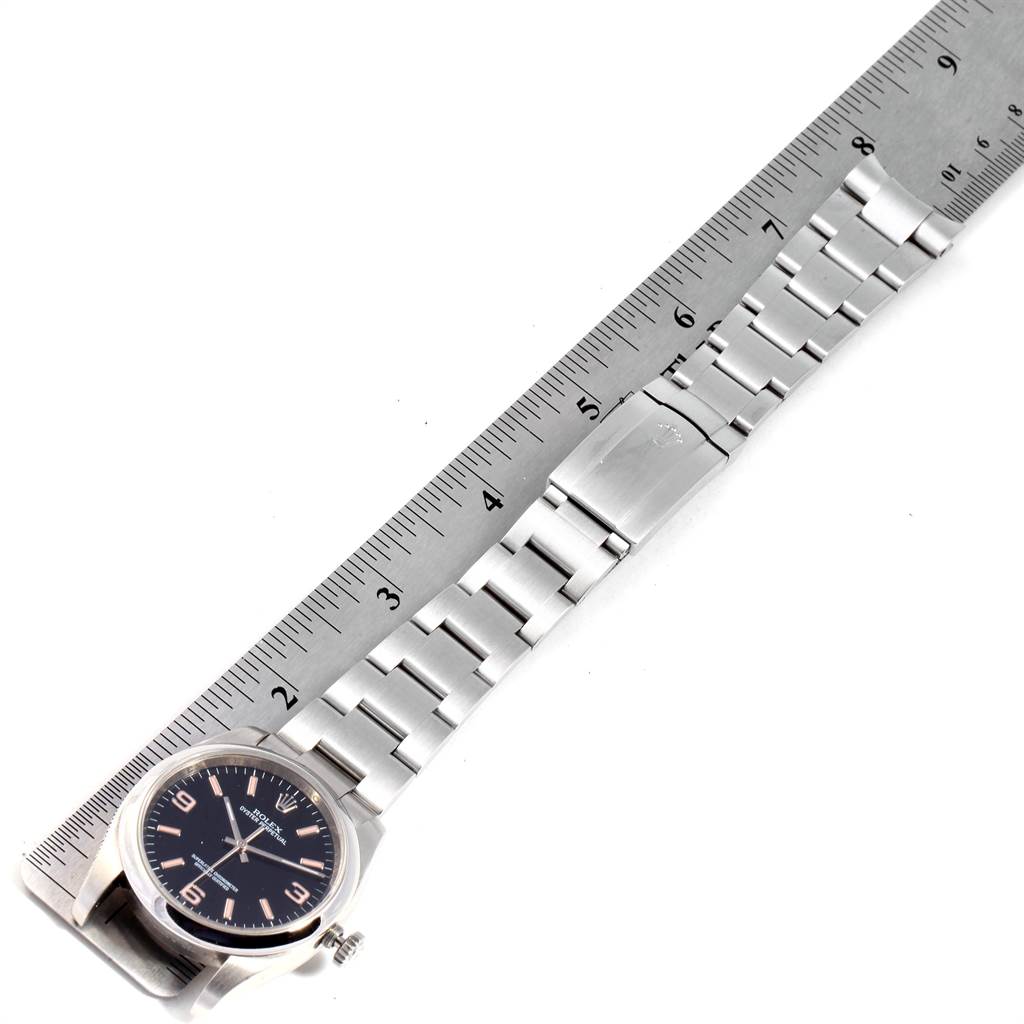 This image shows a top-down view of a Rolex Oyster Perpetual 116000 Men's Stainless Steel Black Dial 116000 Men's Stainless Steel Black Dial watch, highlighting the face, bracelet, and a ruler for scale.