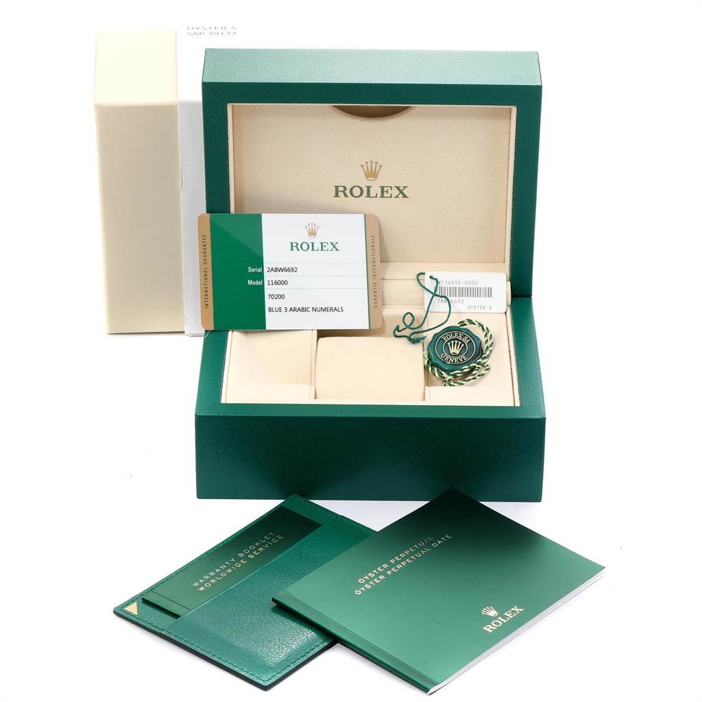 The image shows an open box for a Rolex Oyster Perpetual 116000 Men's Stainless Steel Blue Dial 116000 Men's Stainless Steel Blue Dial watch including authenticity cards, booklets, and a tag.
