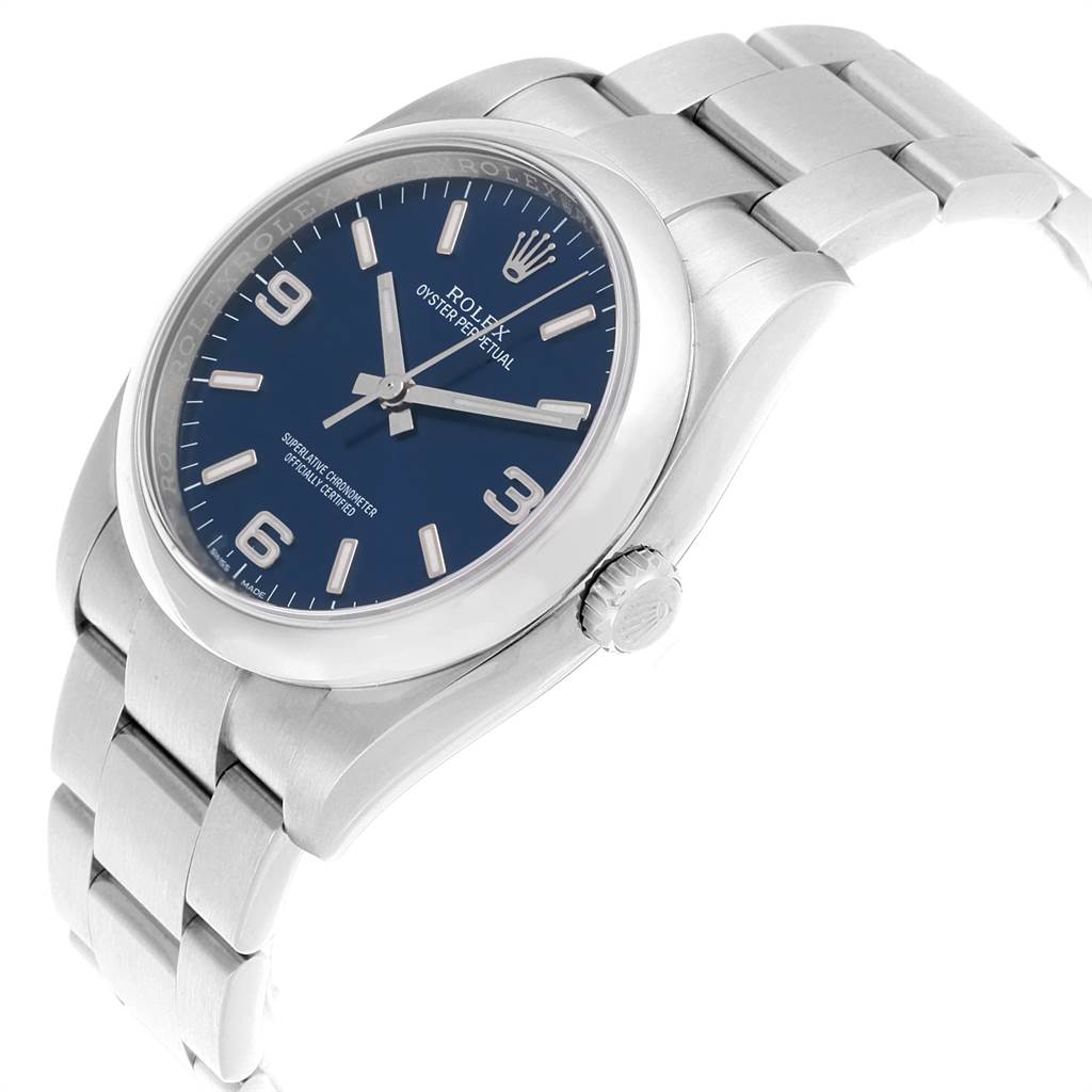 The image shows a Rolex Oyster Perpetual 116000 Men's Stainless Steel Blue Dial 116000 Men's Stainless Steel Blue Dial watch at a slight angle, displaying its blue dial, crown, and stainless steel bracelet.