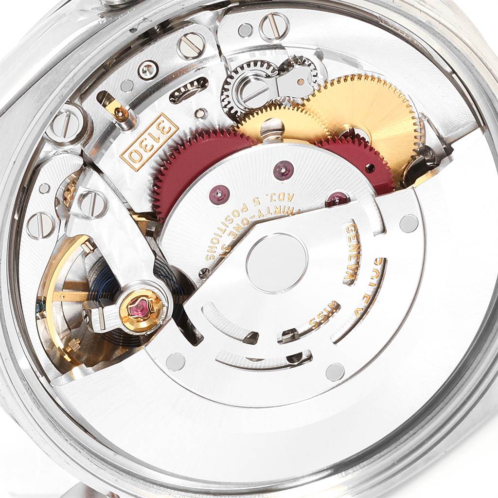 The image shows a close-up of the movement mechanism of a Rolex Oyster Perpetual 114200 Men's Stainless Steel Champagne Dial 114200 Men's Stainless Steel Champagne Dial watch, highlighting gears and internal components.