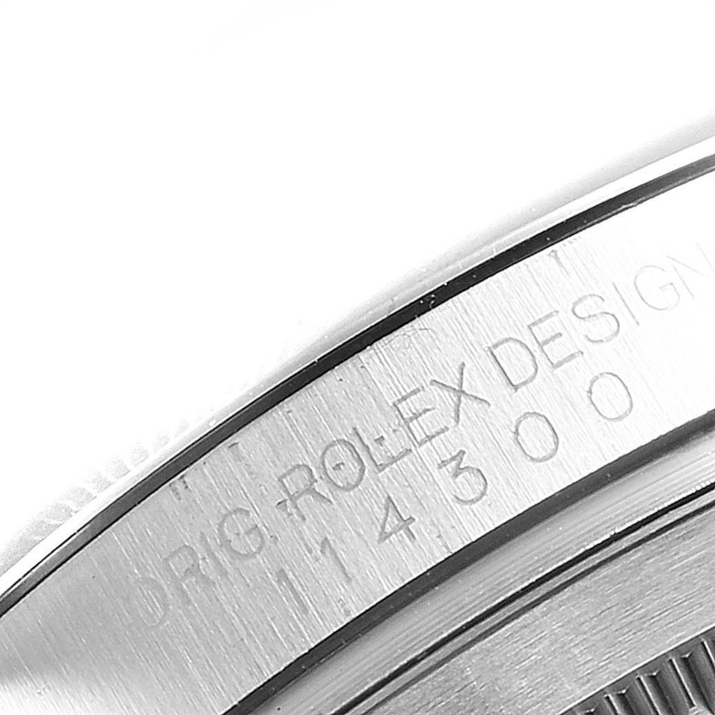 The image shows a close-up of the side of a Rolex Oyster Perpetual 114300 Men's Stainless Steel Blue Dial 114300 Men's Stainless Steel Blue Dial watch with the model number 114300 engraved.