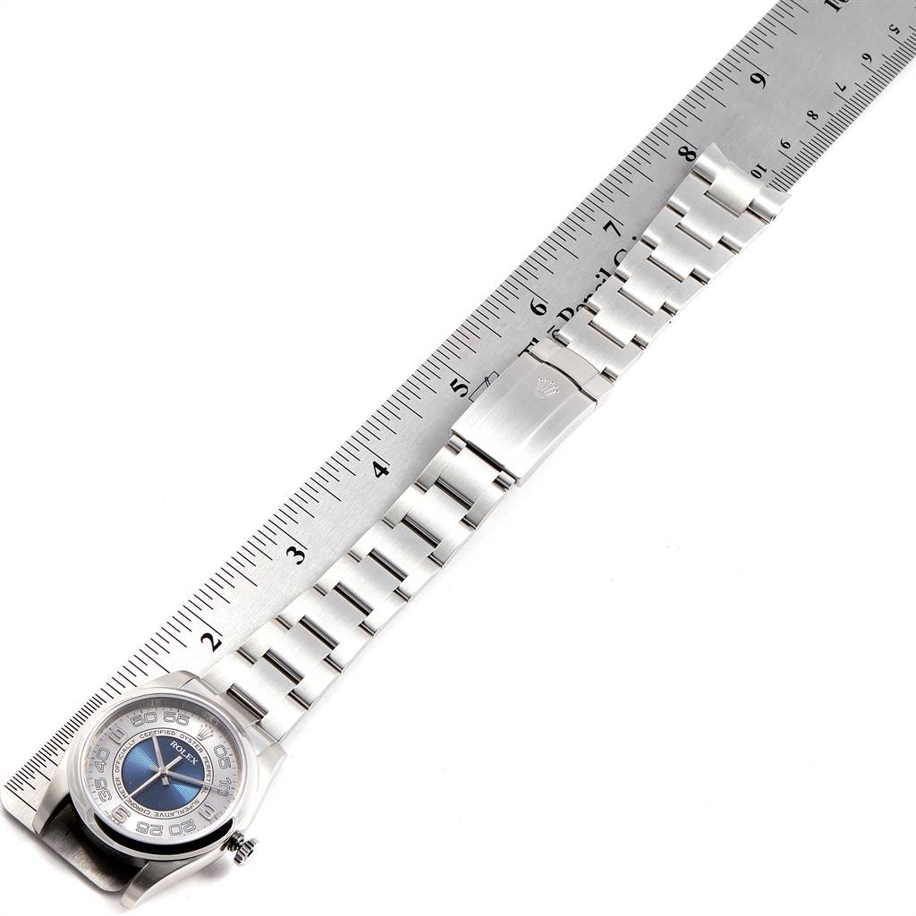 The image shows a top view of a Rolex Oyster Perpetual 116000 Men's Stainless Steel Silver Dial 116000 Men's Stainless Steel Silver Dial watch with its bracelet stretched alongside a ruler.