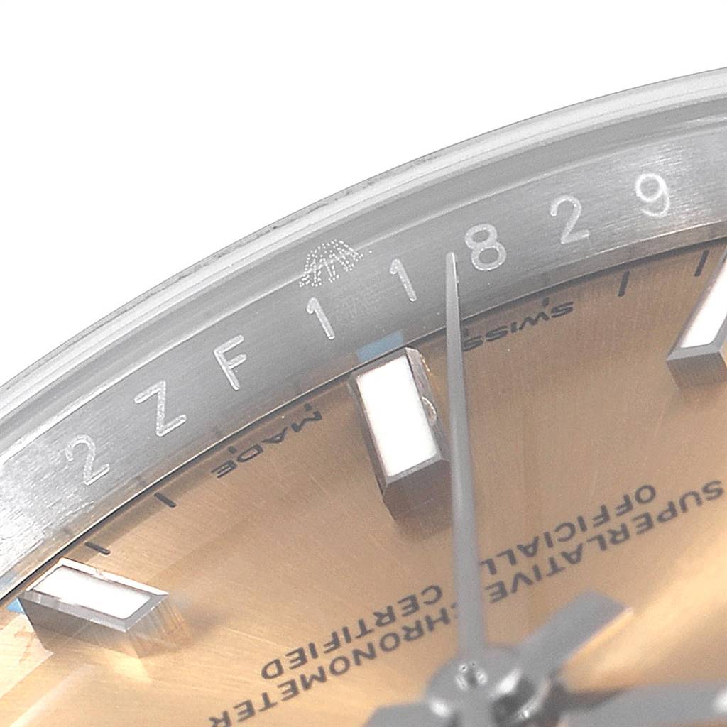 The image shows a close-up of the dial and part of the bezel of a Rolex Oyster Perpetual 114200 Men
s Stainless Steel Champagne Dial 114200 Men
s Stainless Steel Champagne Dial watch.