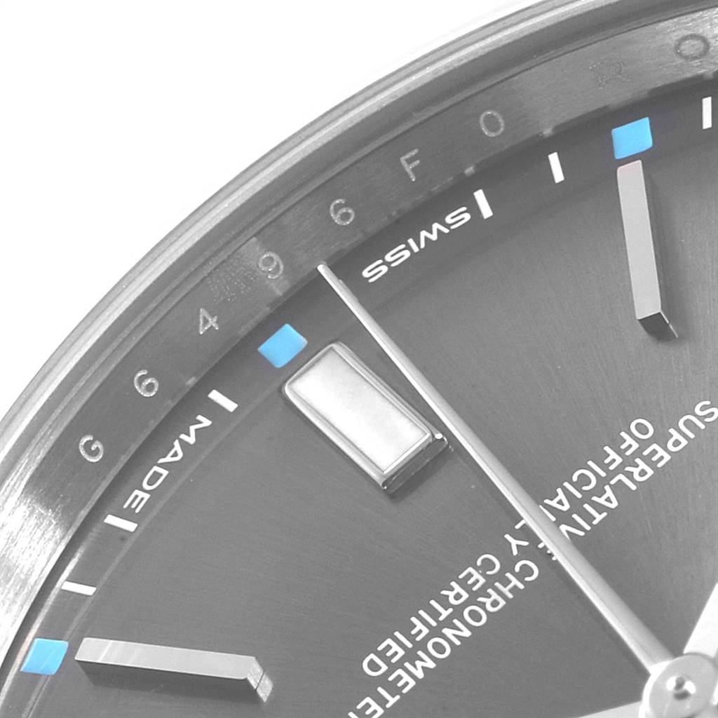 The image shows a close-up of the dial and hands of a Rolex Oyster Perpetual 114300 Men's Stainless Steel Silver Dial 114300 Men's Stainless Steel Silver Dial watch, highlighting the hour markers and part of the text.