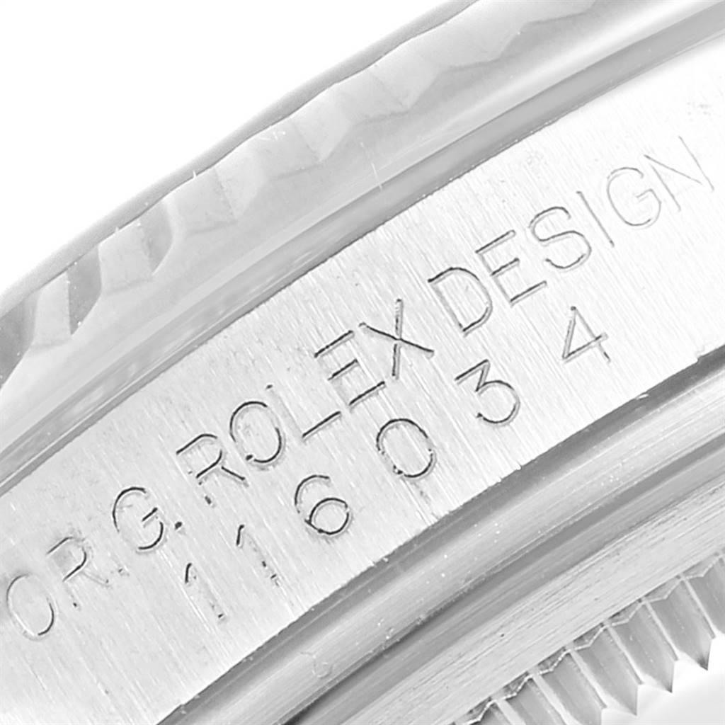 This close-up image of a Rolex Oyster Perpetual 116034 Men
s Stainless Steel Black Dial 116034 Men
s Stainless Steel Black Dial watch shows the engraved bezel with text "ROLEX DESIGN" and a model number.