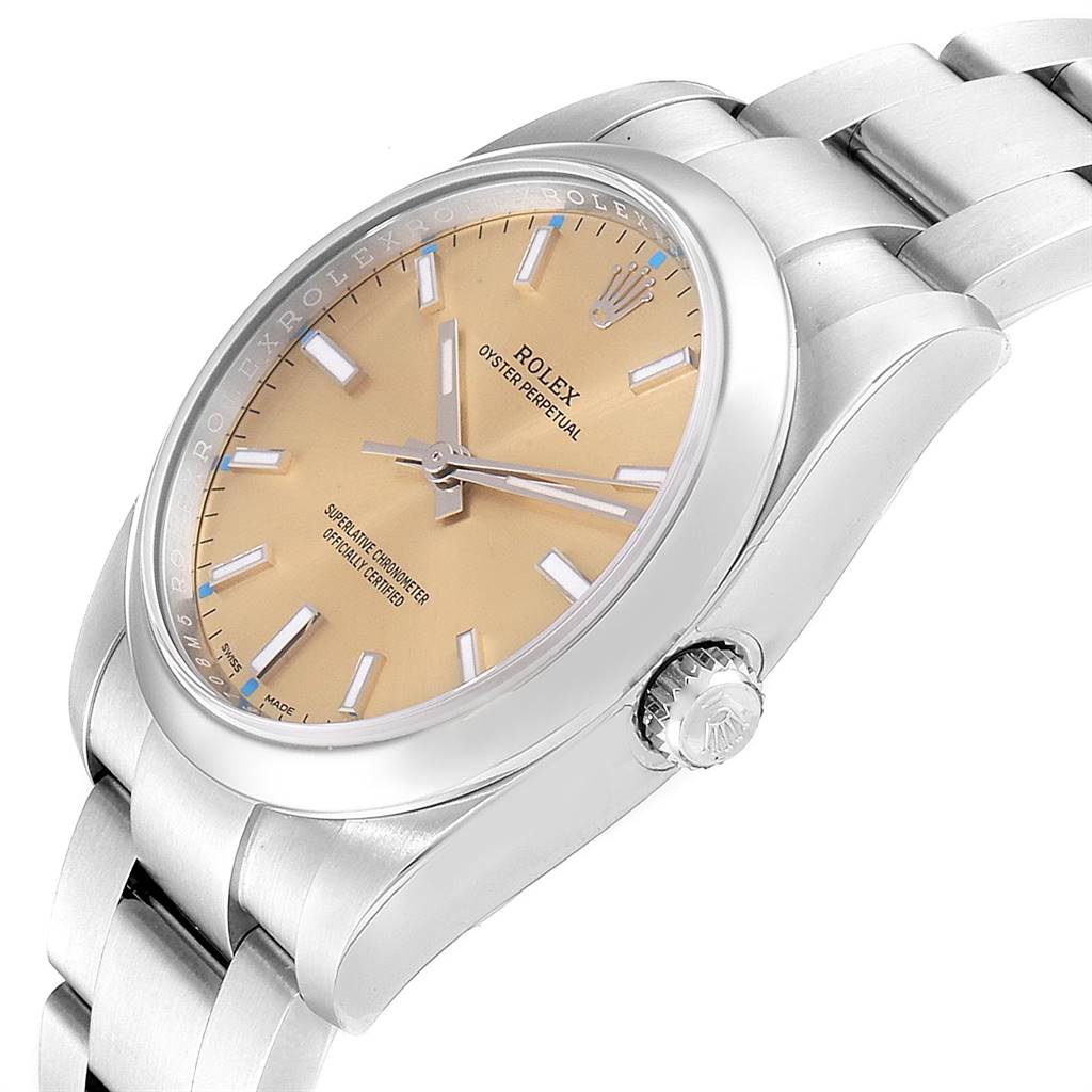 The image shows a Rolex Oyster Perpetual 114200 Men
s Stainless Steel Champagne Dial 114200 Men
s Stainless Steel Champagne Dial watch at a tilted angle highlighting the face, crown, and the beginning of the band.