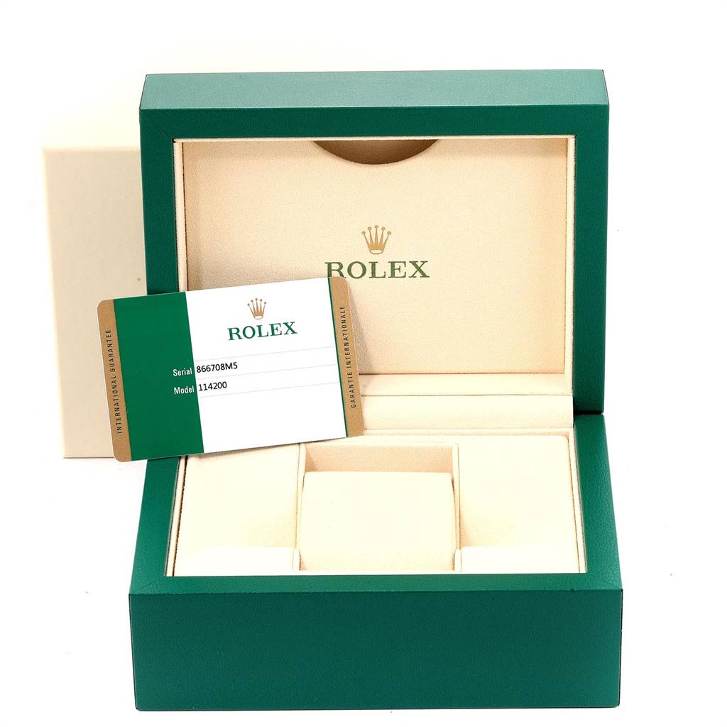 The image shows the presentation box and guarantee card for a Rolex Oyster Perpetual 114200 Men
s Stainless Steel Champagne Dial 114200 Men
s Stainless Steel Champagne Dial watch model 114200.