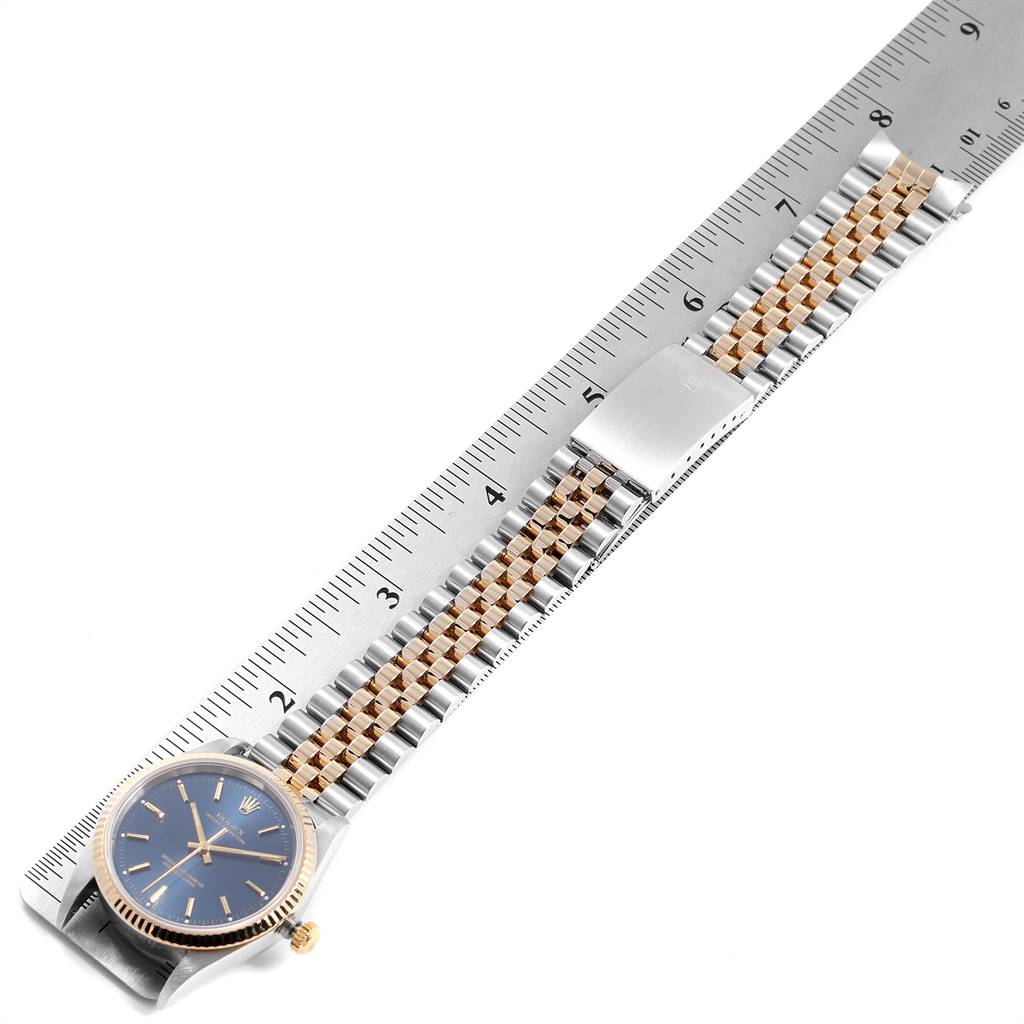 The image shows a Rolex Oyster Perpetual 14233 Men's Steel and Gold (two tone) Blue Dial 14233 Men's Steel and Gold (two tone) Blue Dial watch with a bi-metal bracelet laid flat against a ruler, highlighting the watch face and clasp.