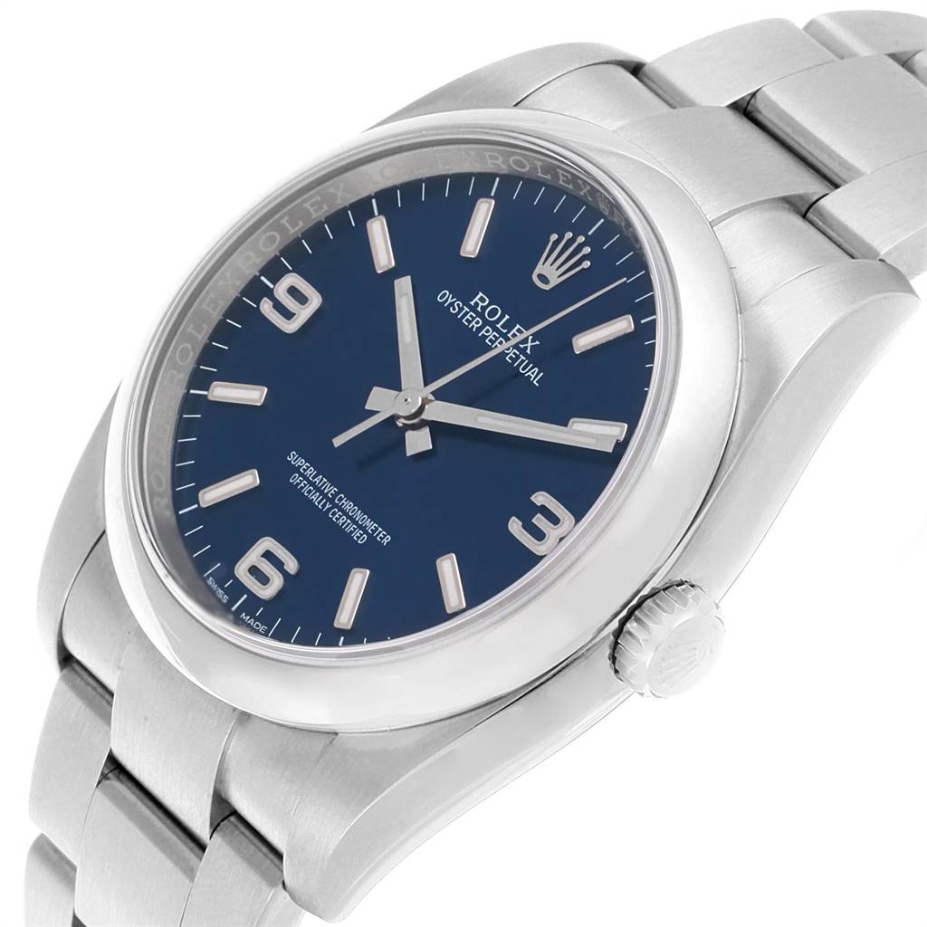 The image shows a Rolex Oyster Perpetual 116000 Men's Stainless Steel Blue Dial 116000 Men's Stainless Steel Blue Dial watch at an angle displaying the dial, case, crown, and part of the bracelet.