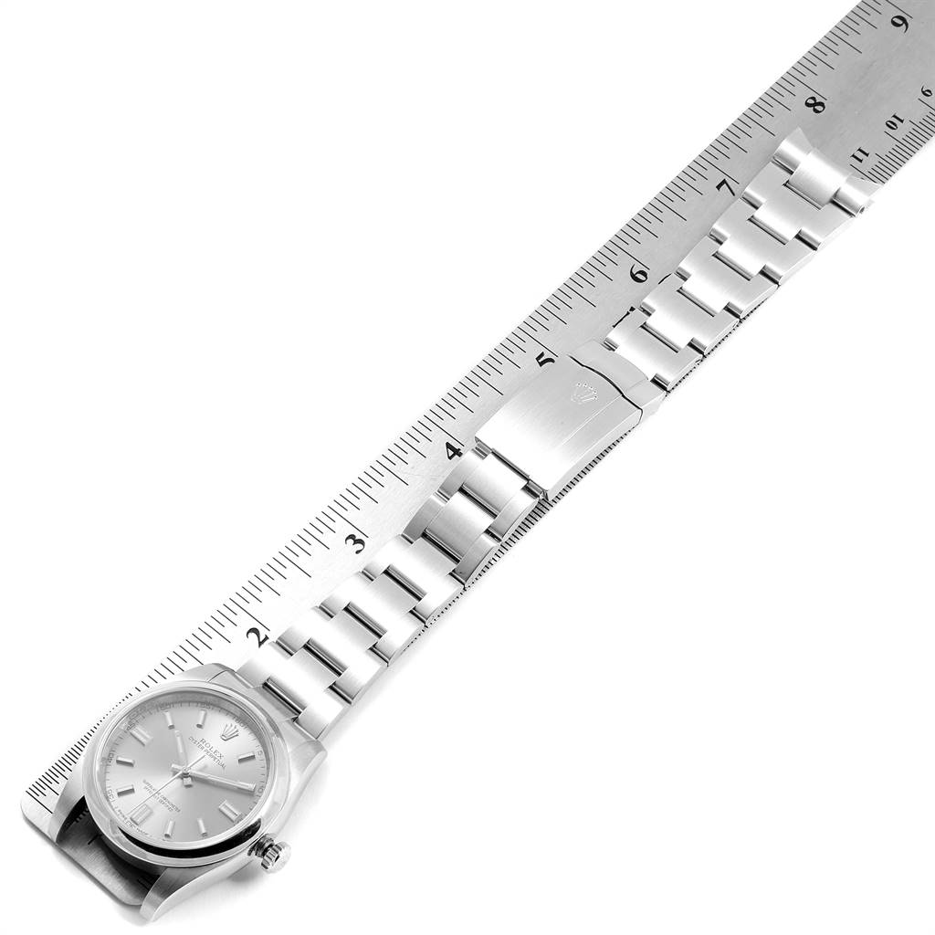 The image shows a top-down view of a Rolex Oyster Perpetual 116000 Men's Stainless Steel Grey Dial 116000 Men's Stainless Steel Grey Dial watch, including the face, bracelet, and clasp alongside a ruler.