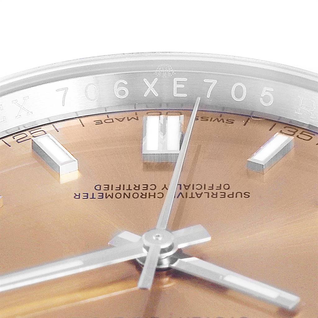 This close-up image of the Rolex Oyster Perpetual 116000 Men
s Stainless Steel Champagne Dial 116000 Men
s Stainless Steel Champagne Dial model shows the dial, hands, and part of the bezel with visible engravings.