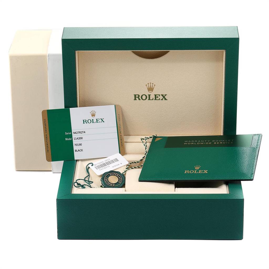 The image shows the packaging, warranty booklet, tag, and card for the Rolex Oyster Perpetual 114200 Men's Stainless Steel Black Dial 114200 Men's Stainless Steel Black Dial model.
