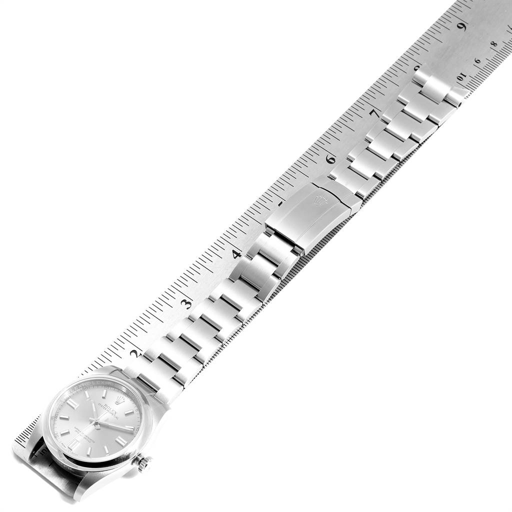 The image shows a side angle view of a Rolex Oyster Perpetual 116000 Men's Stainless Steel Grey Dial 116000 Men's Stainless Steel Grey Dial watch, displaying the face and bracelet alongside a ruler.