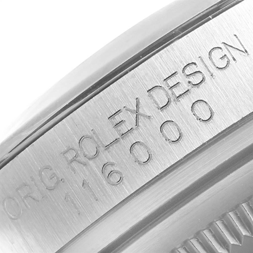 The image shows a close-up of the side of a Rolex Oyster Perpetual 116000 Men's Stainless Steel Grey Dial 116000 Men's Stainless Steel Grey Dial watch with its model number engraved.