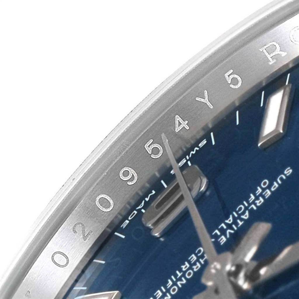 The image shows a close-up of the dial with part of the bezel of a Rolex Oyster Perpetual 114200 Men's Stainless Steel Blue Dial 114200 Men's Stainless Steel Blue Dial watch.