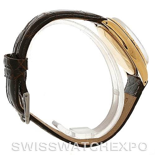 This side view image of a Rolex Oyster Perpetual Men
s Yellow Gold White Dial Men
s Yellow Gold White Dial watch shows the watch case, crown, and leather strap with a buckle.