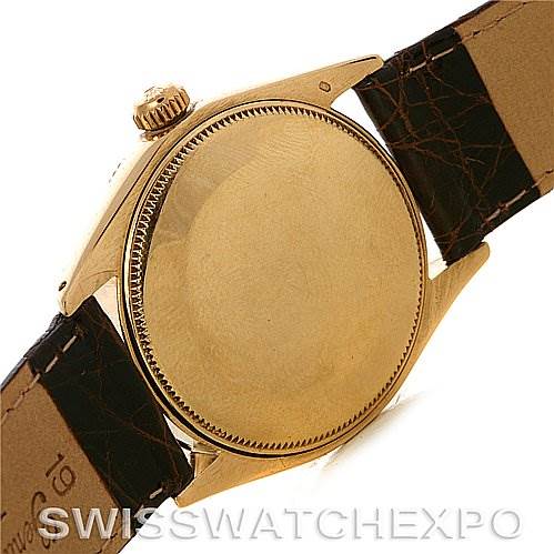 This image shows the back case and part of the leather strap of a Rolex Oyster Perpetual Men
s Yellow Gold White Dial Men
s Yellow Gold White Dial watch.