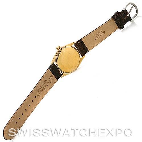 The image shows the back of a Rolex Oyster Perpetual Men
s Yellow Gold White Dial Men
s Yellow Gold White Dial watch with its leather strap extended and the case back visible.
