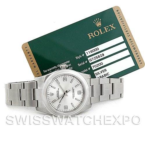 The image shows a Rolex Oyster Perpetual 116000 Men
s Stainless Steel Silver Dial 116000 Men
s Stainless Steel Silver Dial watch placed flat, with its warranty card visible in the background.