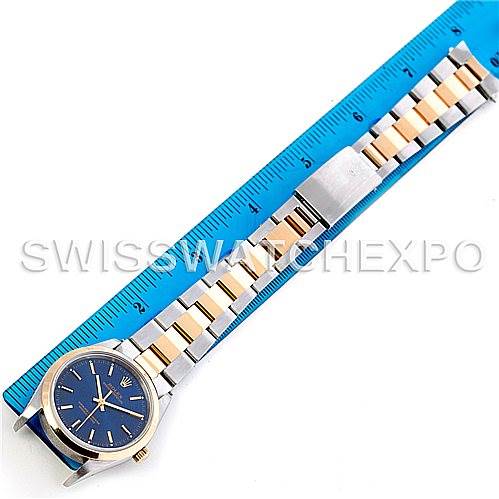 The Rolex Oyster Perpetual 14203 Men's Steel and Gold (two tone) Blue Dial 14203 Men's Steel and Gold (two tone) Blue Dial watch is shown with its full bracelet laid flat next to a ruler, displaying the face and band.