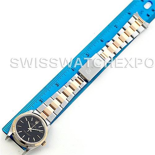The image shows a Rolex Oyster Perpetual 14233 Men's Steel and Gold (two tone) Black Dial 14233 Men's Steel and Gold (two tone) Black Dial watch laid flat next to a blue ruler, highlighting the strap length and detailed view of the face.