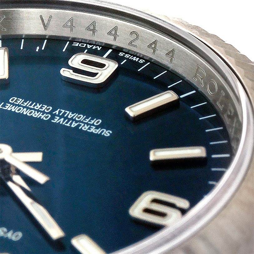 This close-up angle of the Rolex Oyster Perpetual 116034 Men's Stainless Steel Blue Dial 116034 Men's Stainless Steel Blue Dial watch showcases the bezel, part of the dial, and the serial number.