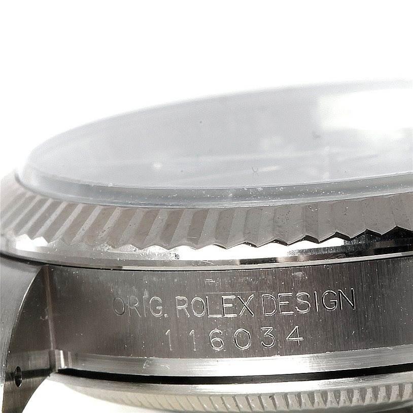 The image shows a close-up, side view of the bezel and case side of the Rolex Oyster Perpetual 116034 Men
s Stainless Steel Black Dial 116034 Men
s Stainless Steel Black Dial, displaying its engraved model number.