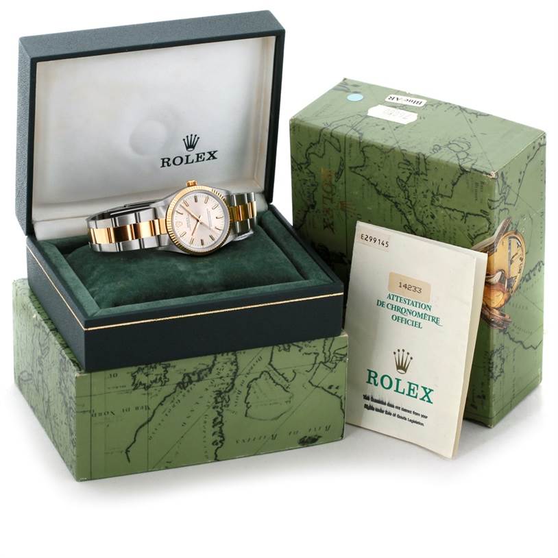 The Rolex Oyster Perpetual 14233 Men's Steel and Gold (two tone) Silver Dial 14233 Men's Steel and Gold (two tone) Silver Dial watch is shown at an angle inside its open box with outer packaging and documentation next to it.