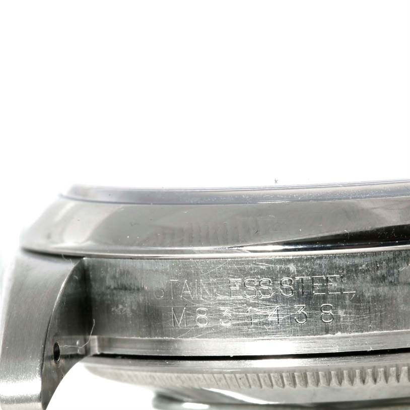 This is a close-up side view of a Rolex Oyster Perpetual M831438 Men's Stainless Steel Black Dial M831438 Men's Stainless Steel Black Dial watch, showing the stainless steel case with engraved text.