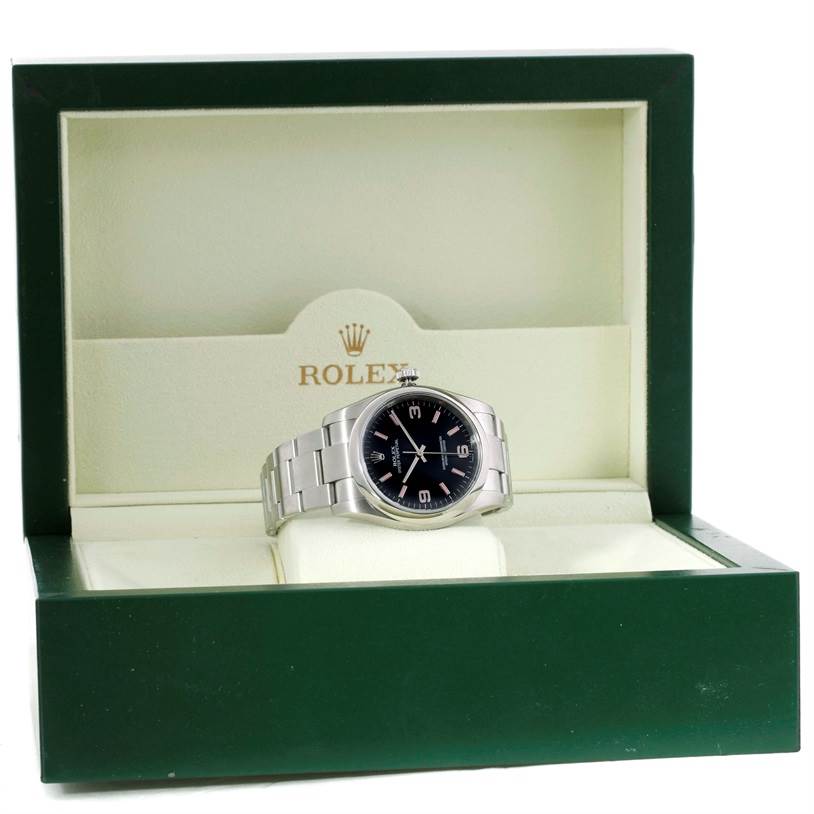 The image shows a Rolex Oyster Perpetual M831438 Men's Stainless Steel Black Dial M831438 Men's Stainless Steel Black Dial watch, front view, placed in its green and beige branded box.
