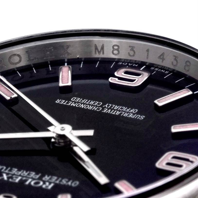 This close-up of the Rolex Oyster Perpetual M831438 Men's Stainless Steel Black Dial M831438 Men's Stainless Steel Black Dial watch shows the dial, hands, numerals, and part of the bezel with the serial number.
