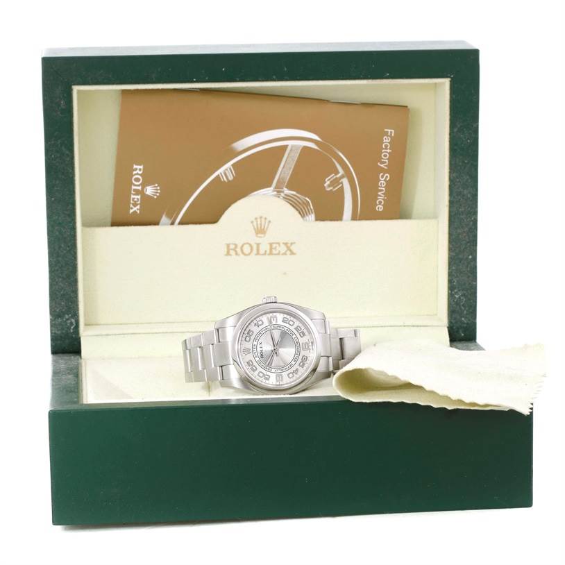The image shows a Rolex Oyster Perpetual 116000 Men's Stainless Steel Silver Dial 116000 Men's Stainless Steel Silver Dial watch inside its open green box, with a cleaning cloth and paperwork included.