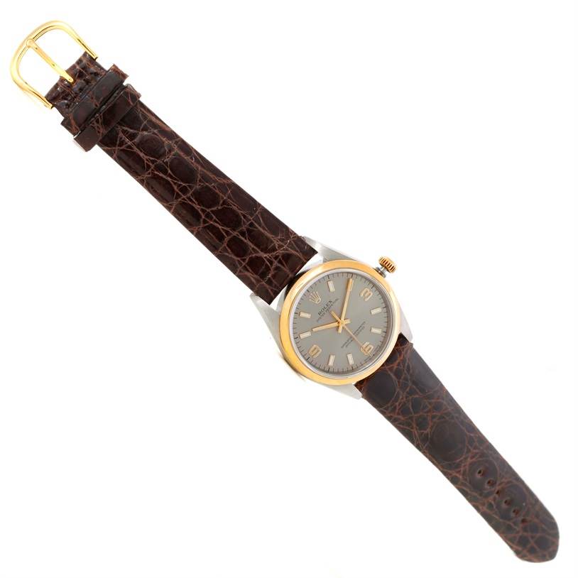 The image shows a top-down view of a Rolex Oyster Perpetual 14203 Men
s Steel and Gold (two tone) Grey Dial 14203 Men
s Steel and Gold (two tone) Grey Dial watch with a brown leather strap and a gold and silver bezel.