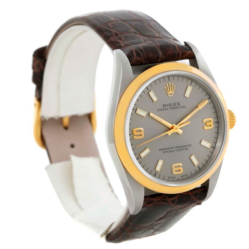 The image shows a Rolex Oyster Perpetual 14203 Men
s Steel and Gold (two tone) Grey Dial 14203 Men
s Steel and Gold (two tone) Grey Dial watch at a slight angle, highlighting its dial, bezel, and brown leather strap.