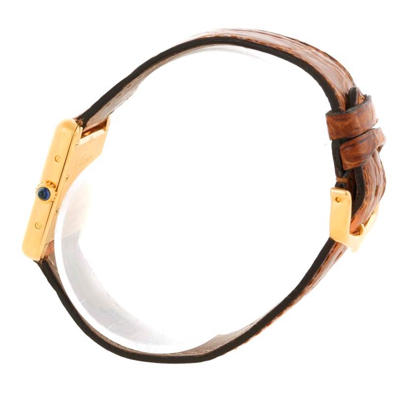 The image shows a side view of a Cartier Tank Louis W1529856 Women's Yellow Gold Silver Dial W1529856 Women's Yellow Gold Silver Dial watch, highlighting its gold case, blue cabochon crown, and brown leather strap.