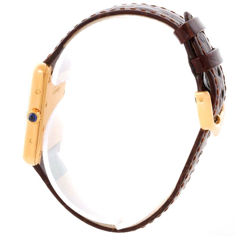 This side view of the Cartier Tank Louis W1529856 Women's Yellow Gold Silver Dial W1529856 Women's Yellow Gold Silver Dial watch model highlights its gold casing, blue sapphire crown, and brown leather strap.