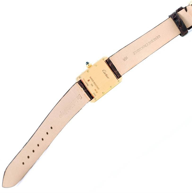 The image shows the underside of a Tank Louis model watch by Cartier, including the case back, part of the strap, and the buckle.