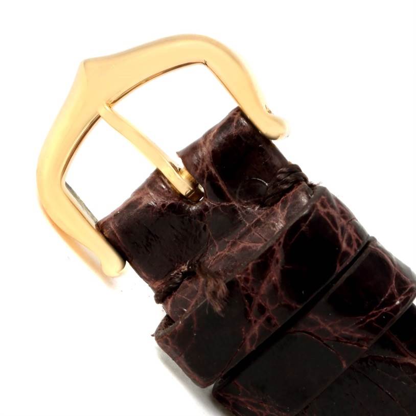 This image shows a close-up of the gold buckle and brown leather strap of the Tank Louis model by Cartier.