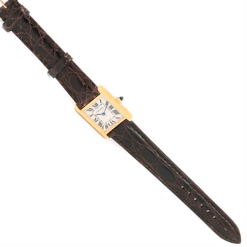 The image shows a top-down view of a Cartier Tank Louis W1529856 Women's Yellow Gold Silver Dial W1529856 Women's Yellow Gold Silver Dial watch, highlighting its square dial, brown leather strap, and gold casing.