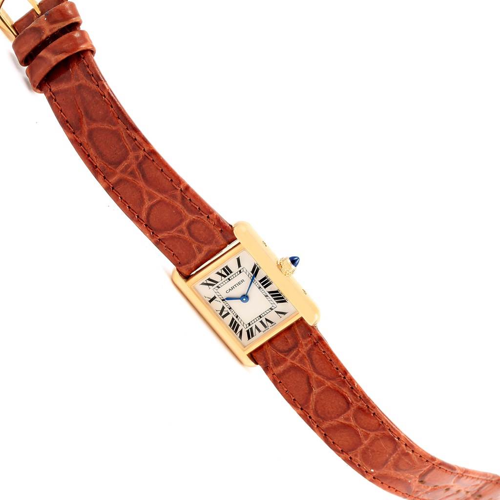 The image shows a Cartier Tank Louis W1529856 Women's Yellow Gold Silver Dial W1529856 Women's Yellow Gold Silver Dial watch from a top-down angle, featuring a gold case, blue hands, and a brown leather strap.