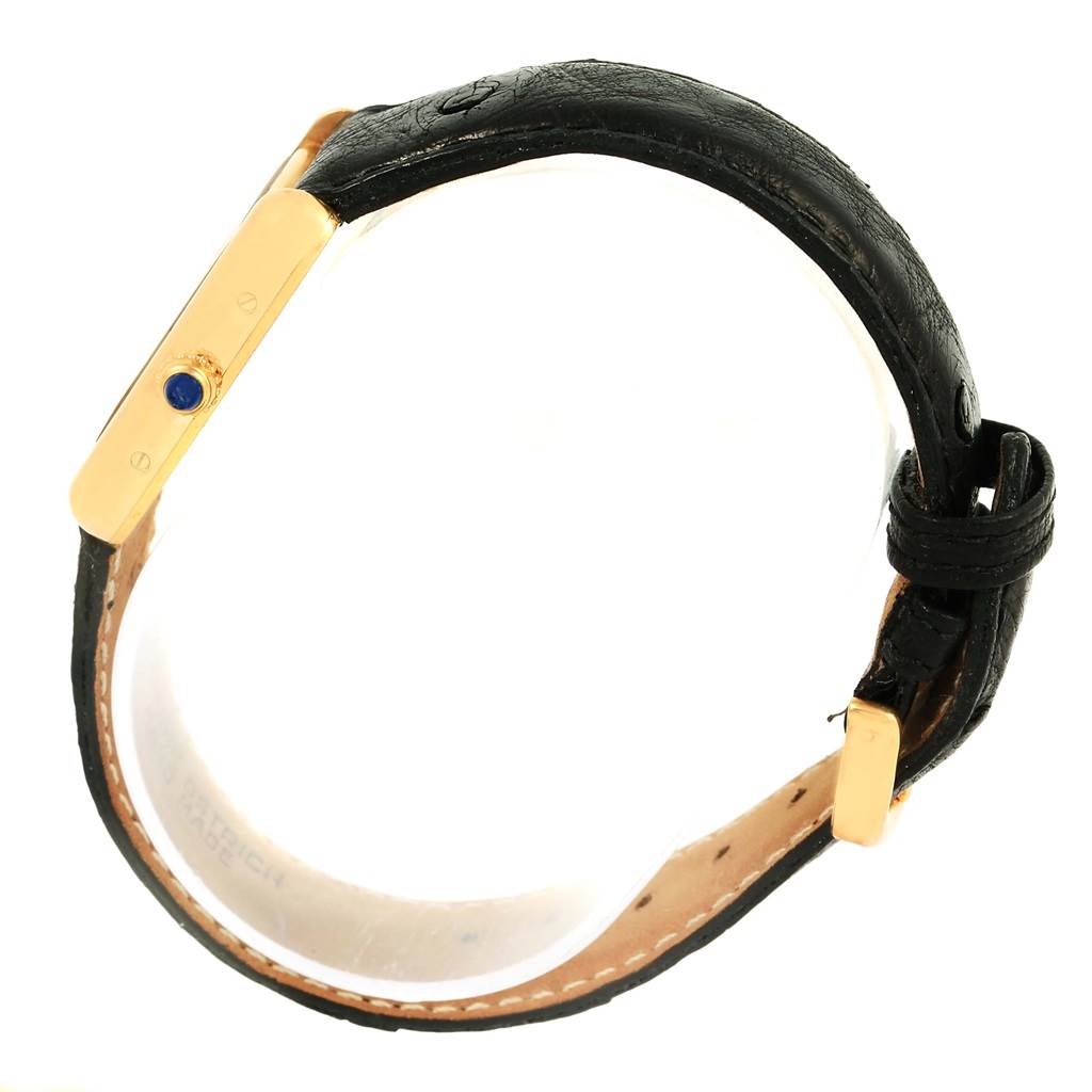 The image shows a side view of the Cartier Tank Louis W1529856 Women's Yellow Gold Silver Dial W1529856 Women's Yellow Gold Silver Dial watch, highlighting its golden case and crown with a blue cabochon, as well as its black leather strap.