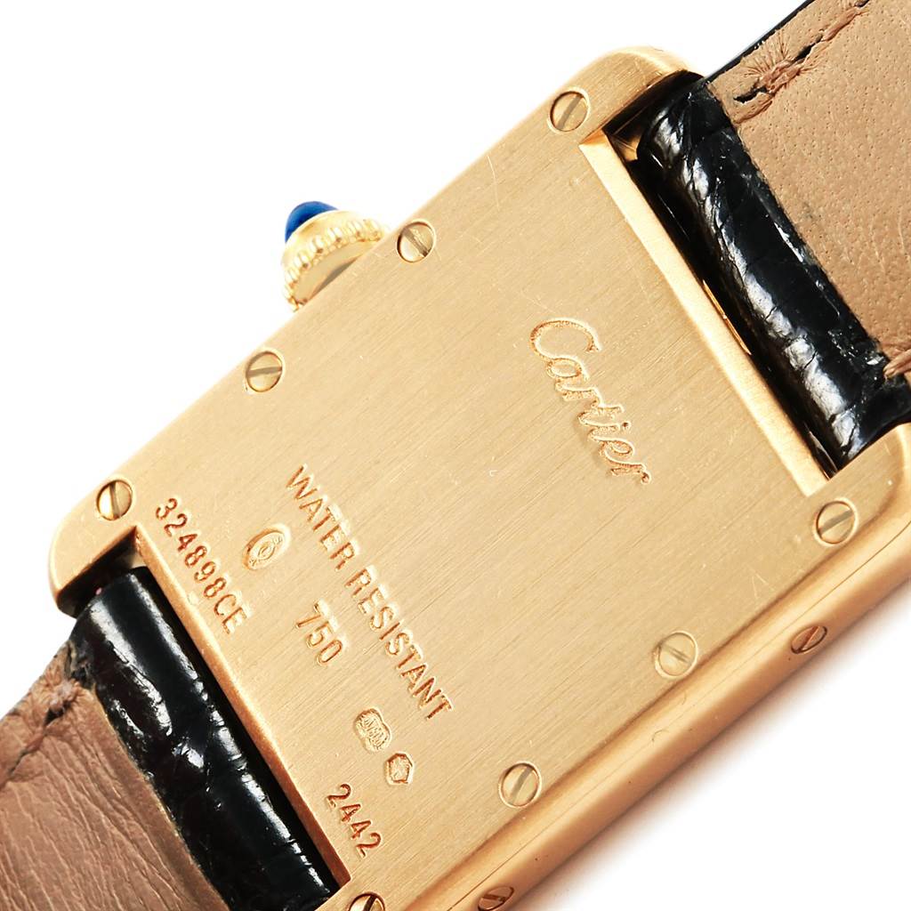 This image shows the back case, crown, and part of the strap of a Cartier Tank Louis W129856 Women
s Yellow Gold Silver Dial W129856 Women
s Yellow Gold Silver Dial watch.