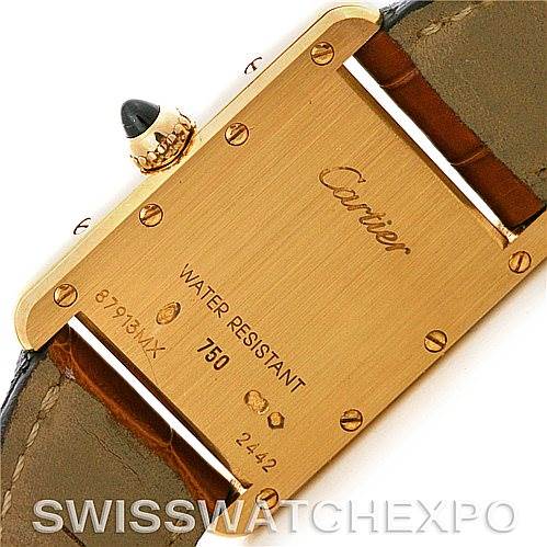 The image shows the back case of a Cartier Tank Louis W1529856 Women's Yellow Gold Silver Dial W1529856 Women's Yellow Gold Silver Dial watch, featuring inscriptions and a visible screw-down crown with a blue jewel.