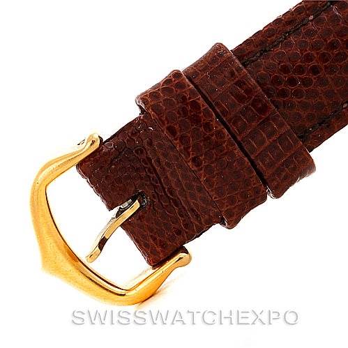 The image shows a close-up of the brown leather strap and gold buckle of a Tank Louis model by Cartier.
